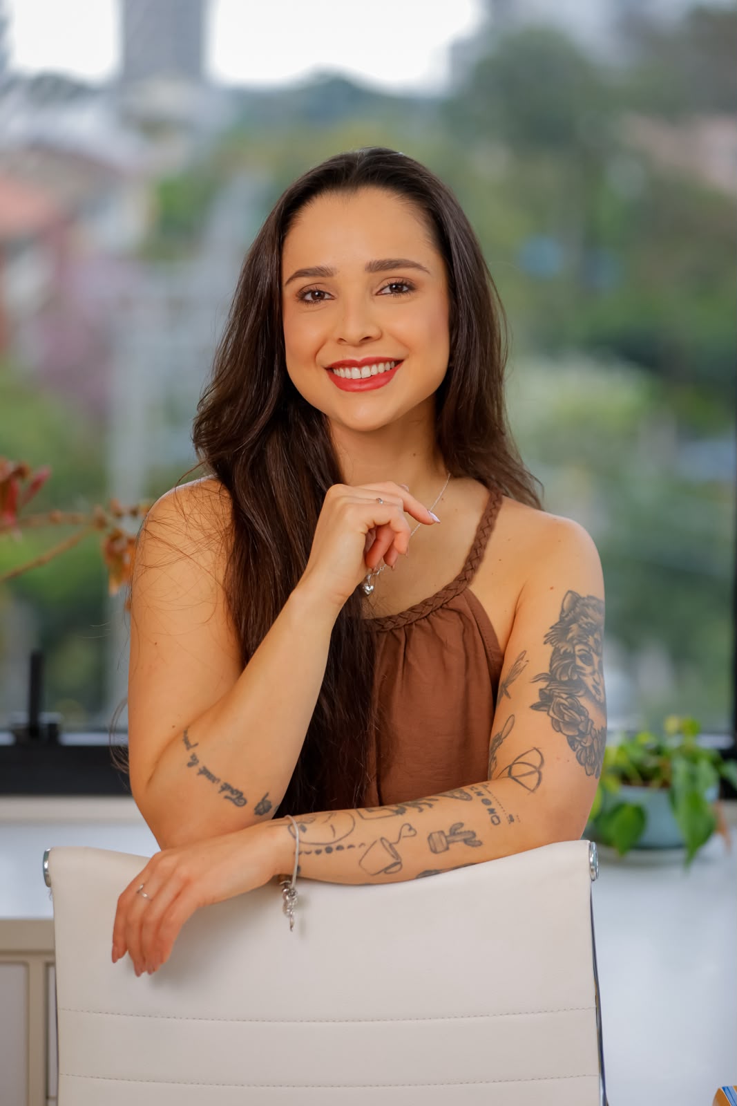 Luiza Ramires sorrindo, apoiada no encosto de uma cadeira